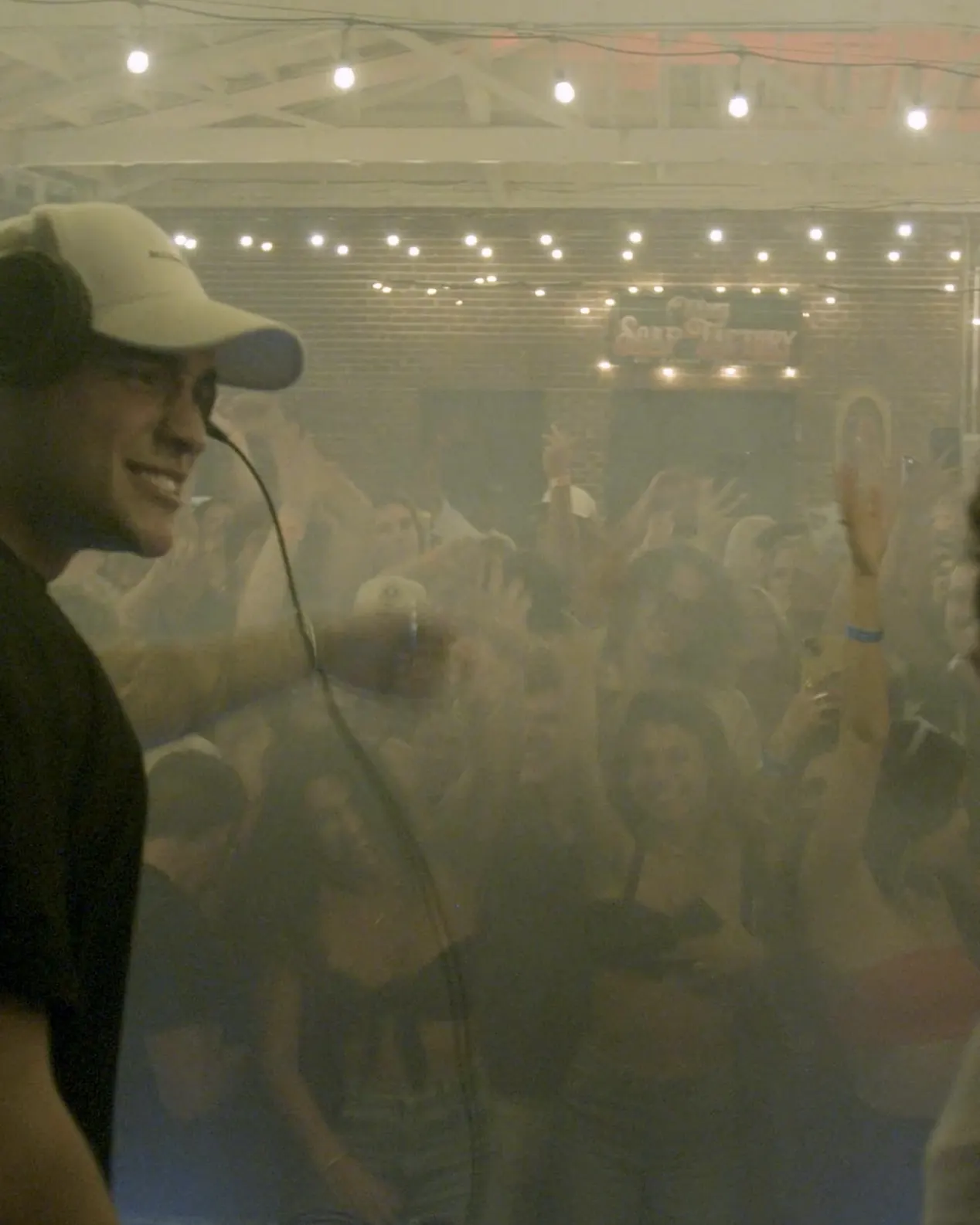 A singer in a cap with the hazy crowd behind him