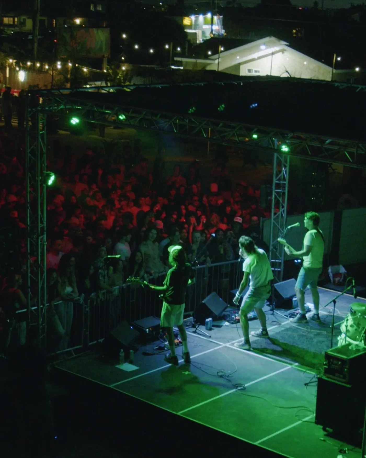 A band on a green-lit stage over a packed crowd at Local Lineup 3.0