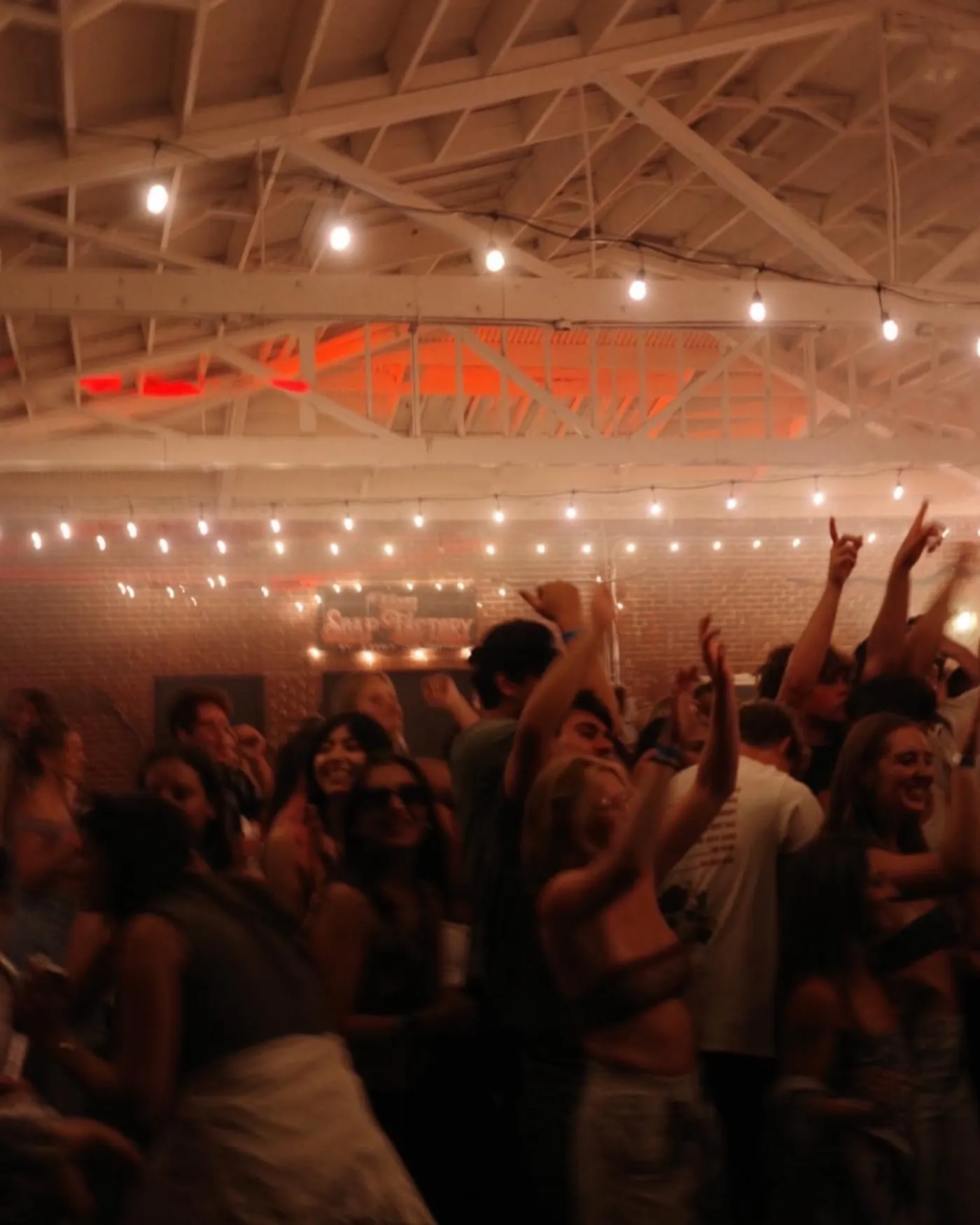 Hands up under string lights